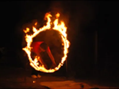 Performer dancing at campfire on the beach sand