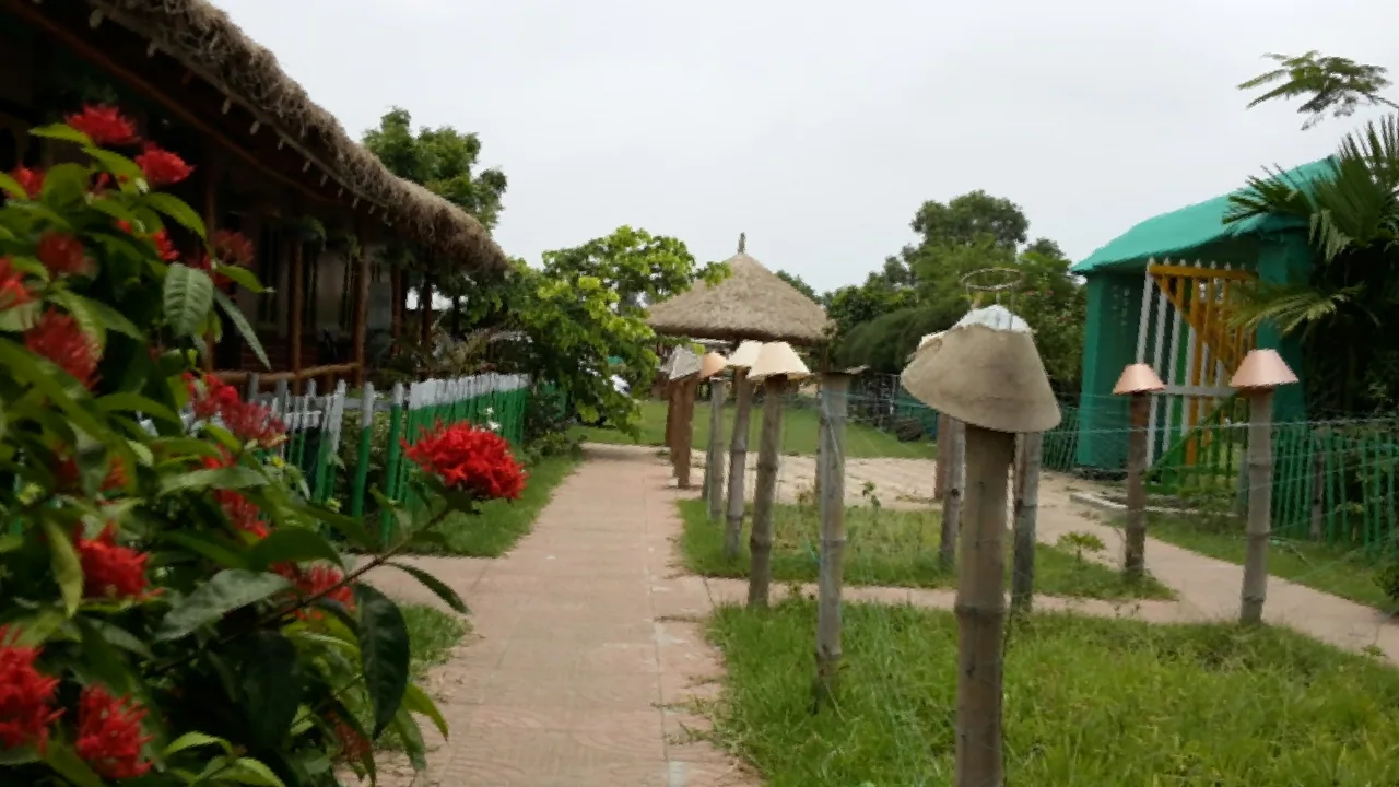 Bamboo-lit garden path with red flowers and thatched huts
