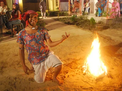 Guest posing by a campfire on the beach sand at night